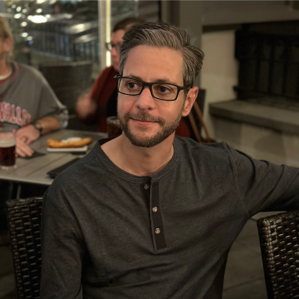 Man wearing glasses at a restaurant with a gray Henley