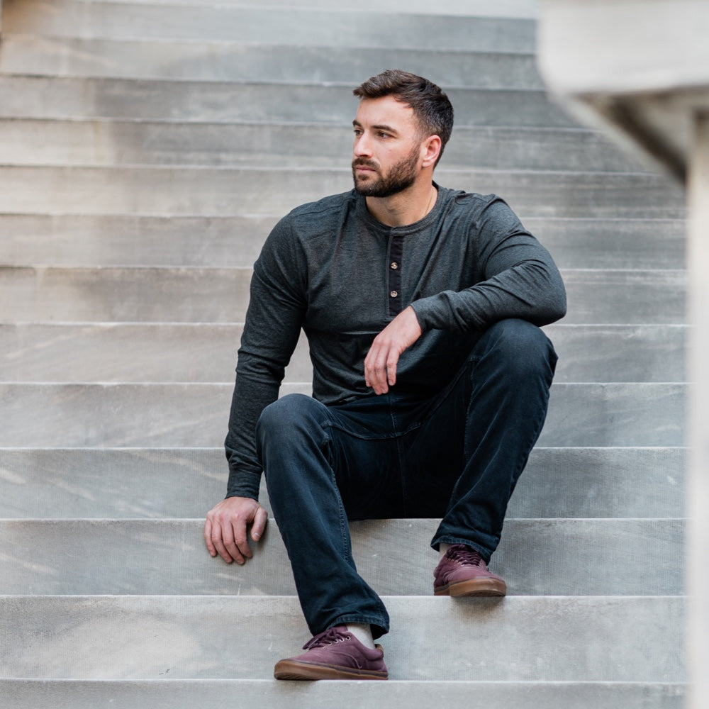Man wearing a Henley's gray shirt sitting on a staircase