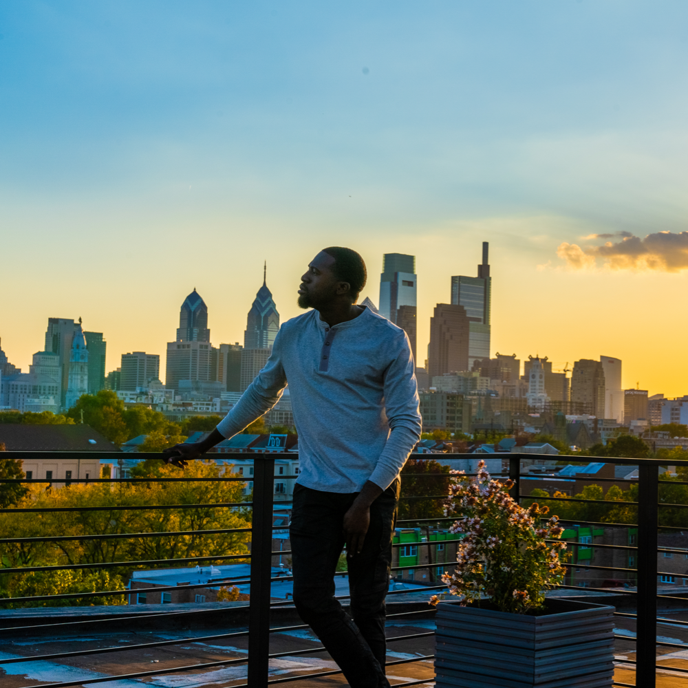 Man wearing a white Henley over looking a city during a sunset